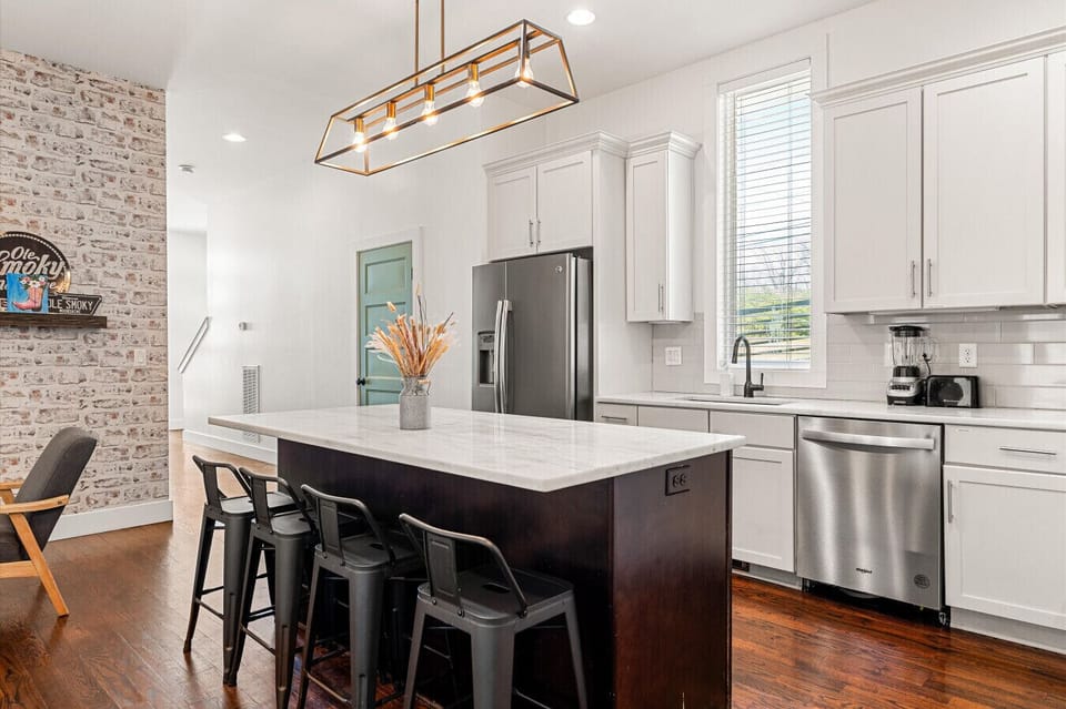 A fully equipped kitchen with a quartz island, gas range, double ovens, and bar seating — everything your group needs to eat, drink, and get ready for Broadway.