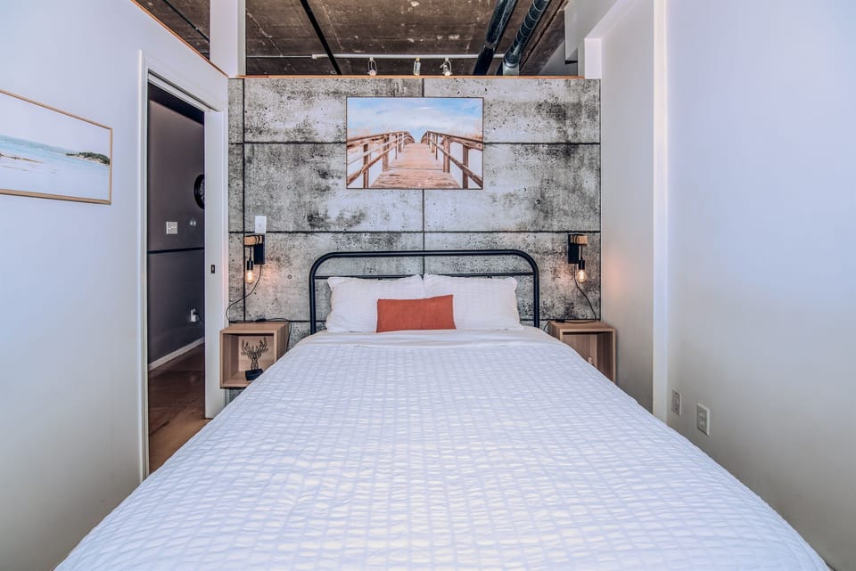 Cozy loft bedroom with a simulated concrete accent wall, vintage touches, and a comfortable queen bed