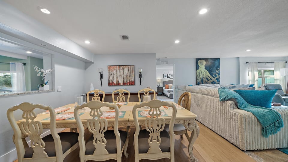 Open-concept dining and living area with an elegant table, sectional sofa.