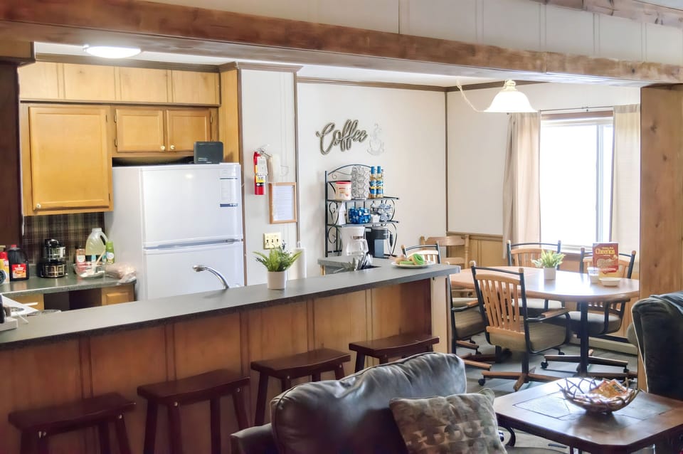 Open kitchen and dining area overlooking the mountains, along with dining table and bar seating, stocked coffee bar, fridge, oven/stove, toaster oven, air fryer, waffle maker & s'mores maker.