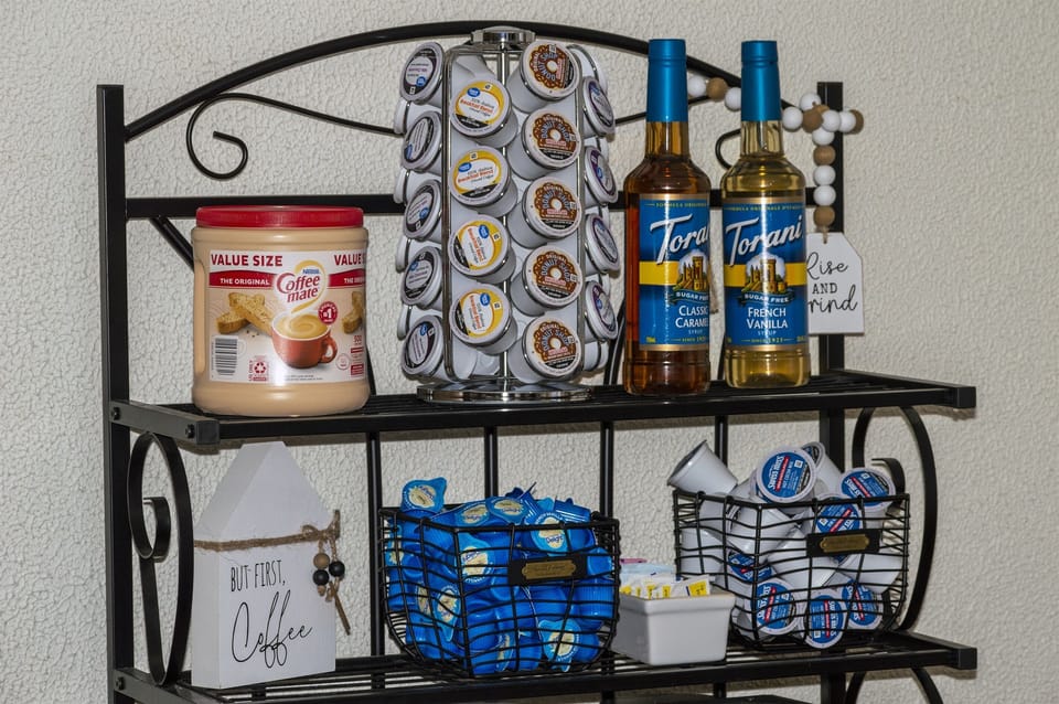 Stocked coffee bar with coffee and hot chocolate k-cups, creamer and sugar-free flavored syrups