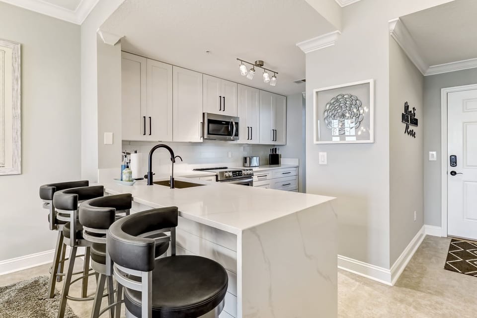 Waterfall Quartz Countertops, Stainless Appliances, Bar Stool Seating for 4 at this Grandeur Kitchen that Opens Up to the Living Space