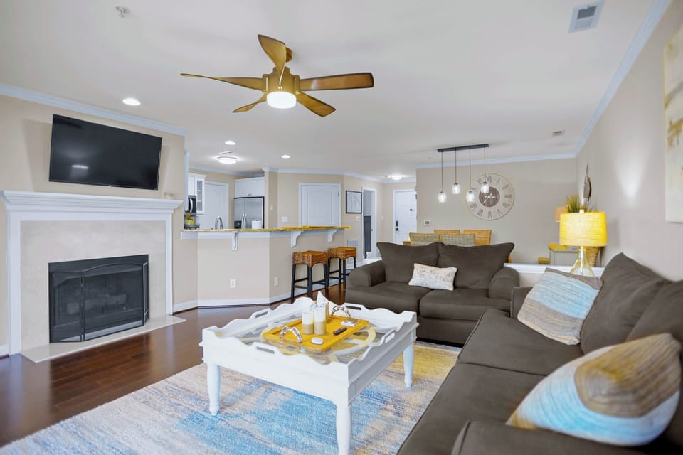 Living room with couch seating options, TV. sliders to the deck and lake views.