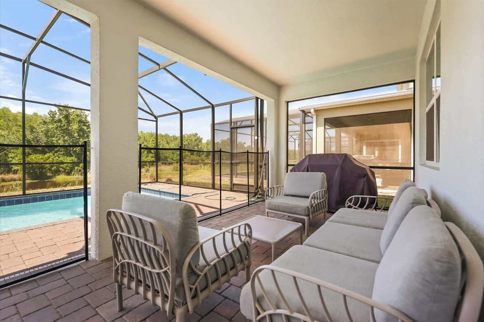 Unwind on the cozy patio with a view of the private pool and lush greenery, perfect for relaxation and outdoor dining.