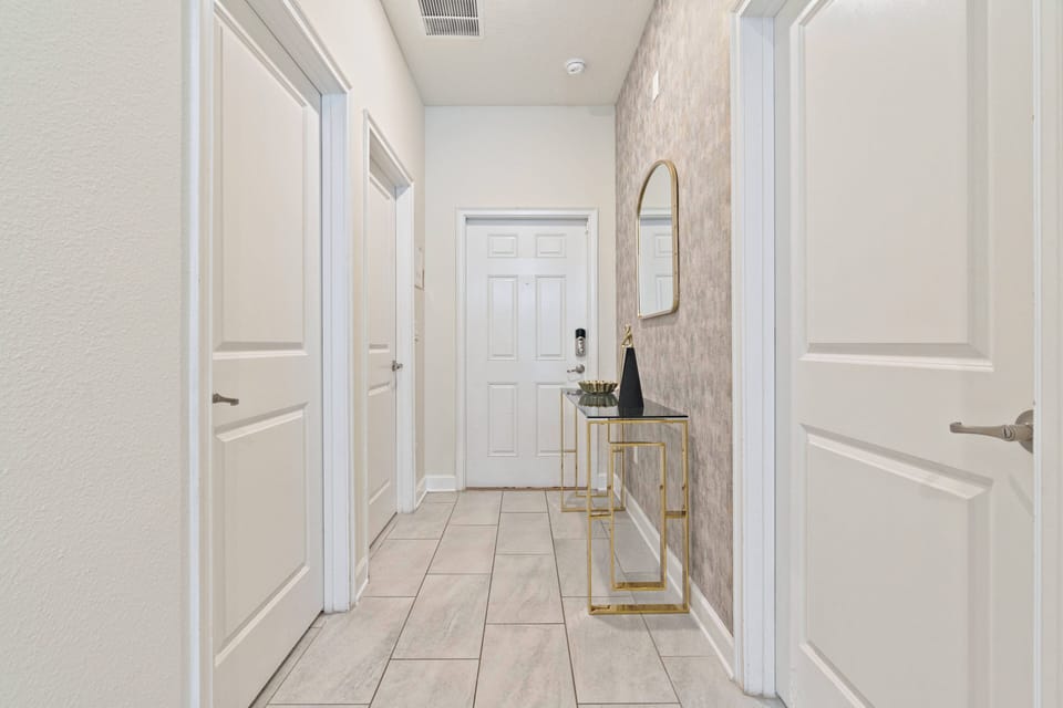 Welcome to this beautifully designed hallway, where natural light accentuates the warm tones of polished tile flooring. A stylish console table and chic mirror create a sophisticated and inviting atmosphere for all guests.