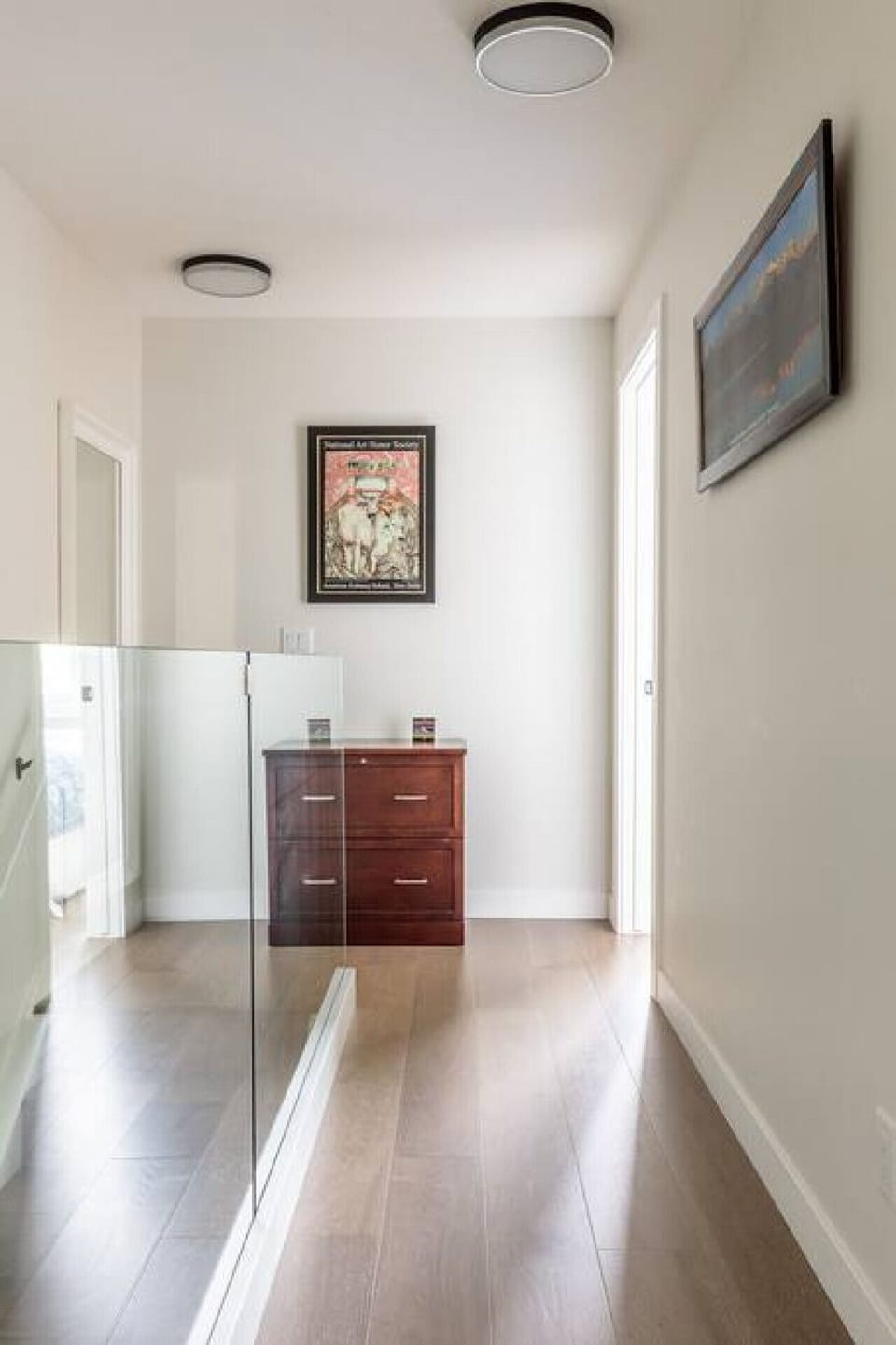 View of top floor hallway connecting the two bedrooms with hardwood flooring throughout.