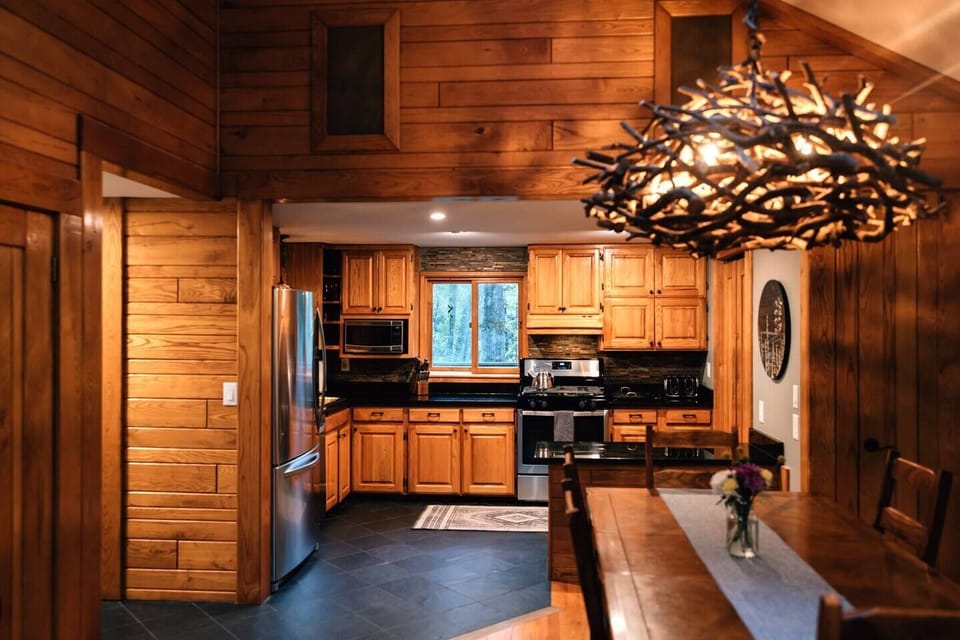 A custom dimmable mountain laurel chandelier over the dining table creates a beautiful glow. Bose surround sound speakers above the kitchen deliver exceptional sound, enhancing the ambiance throughout the open floor plan.