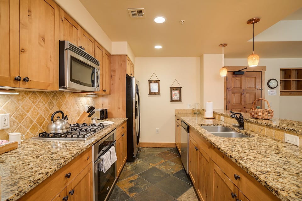 Your fully equipped kitchen invites culinary adventures with granite counters, stainless appliances, and warm wood cabinets creating the perfect cooking retreat.