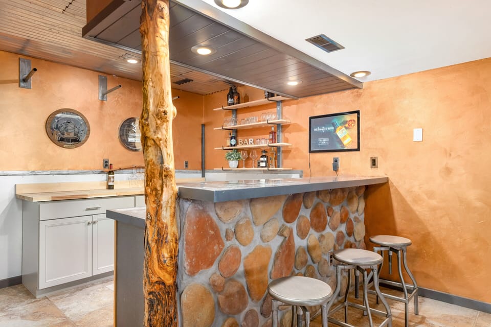Rustic kitchenette with stone bar and stools, ideal for casual gatherings.
