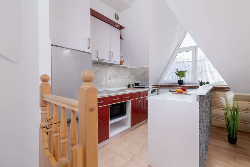 A modern kitchen with red cabinetry and large windows.

