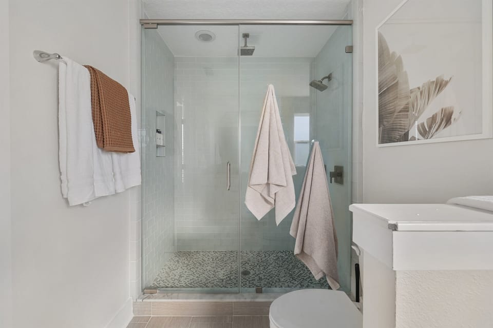 Primary ensuite featuring a large walk-in glass shower.  A refreshing space to start or end your beach day.