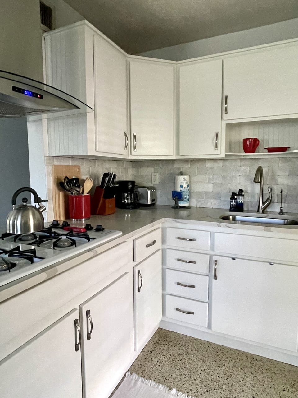 A well equipped kitchen with: toaster, microwave, kettle, blender, coffee maker.