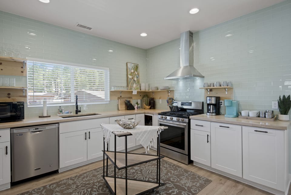 The kitchen is upgraded with butcher block, cabinets, and amazing glass tile