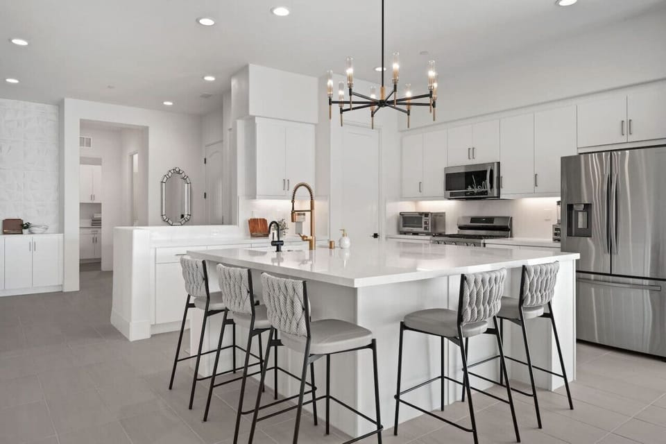 Modern white kitchen w/ large island seating & sleek finishes for effortless gatherings.