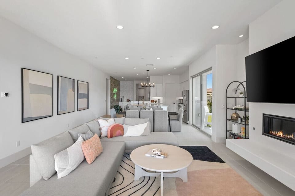 Bright open living space w/ plush seating, sleek fireplace & modern decor.