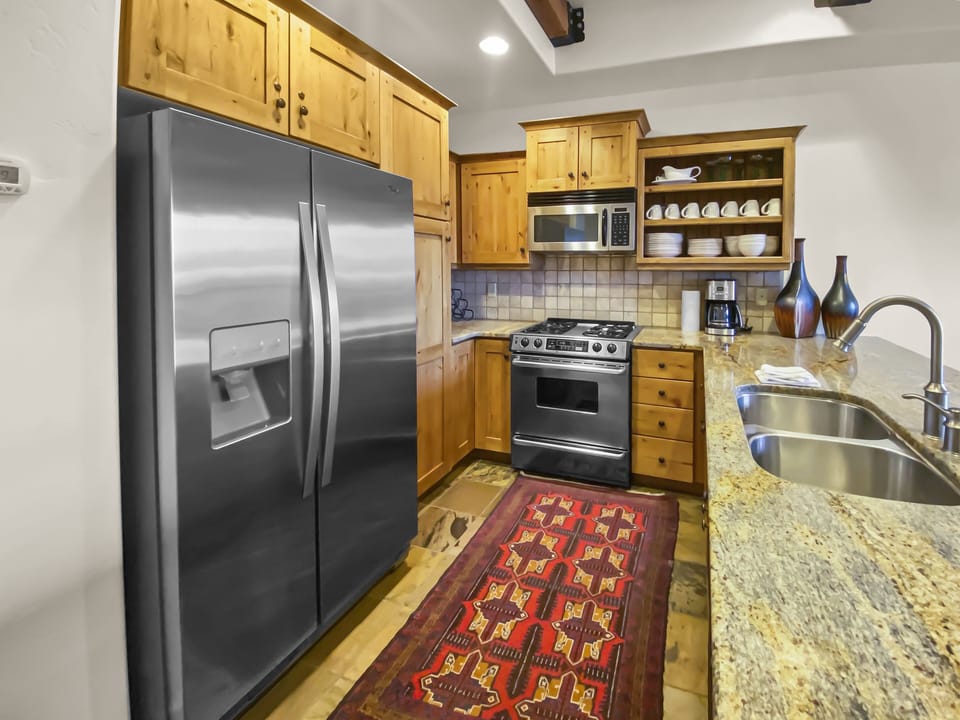 Cook with ease in this bright, gourmet kitchen featuring premium stainless steel appliances, warm wood cabinetry, and expansive granite countertops—an inviting hub for group meals and morning coffee.