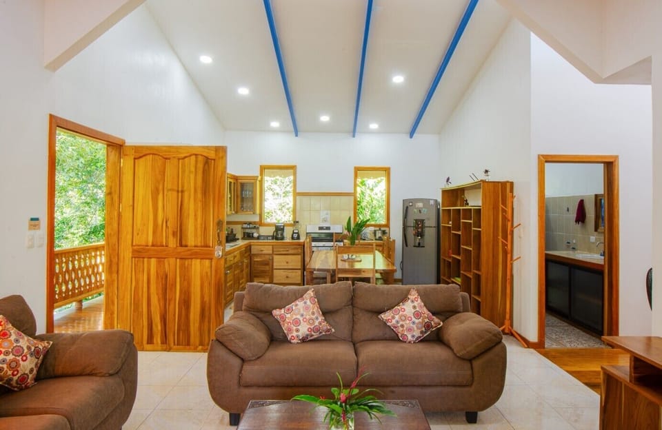 Spacious living area with comfortable seating and fully equipped kitchen, surrounded by natural light and forest views, Blue Maverick in Puerto Viejo