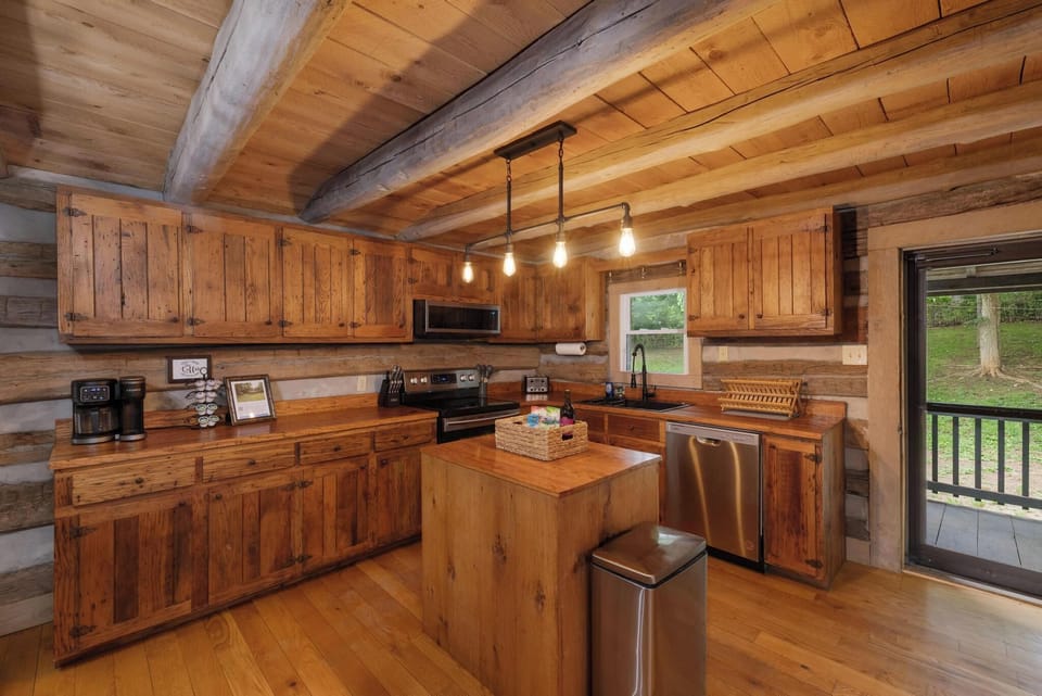 Rustic cabin kitchen with wood beams, island, and deck access