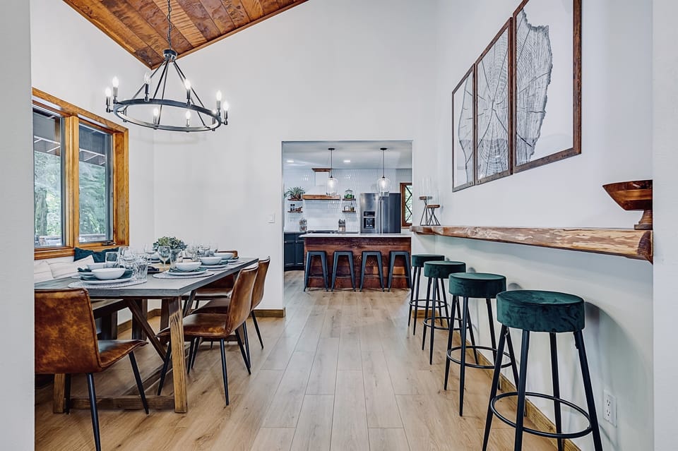 A large dining room with vaulted ceilings, table that seats 12, and a 12ft live-edge bar allows for more seating or works as a buffet table for any meal.