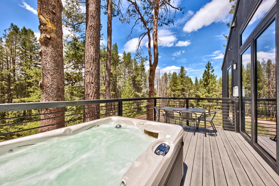 Soak in your private hot tub surrounded by towering pines and endless mountain views on this expansive deck.