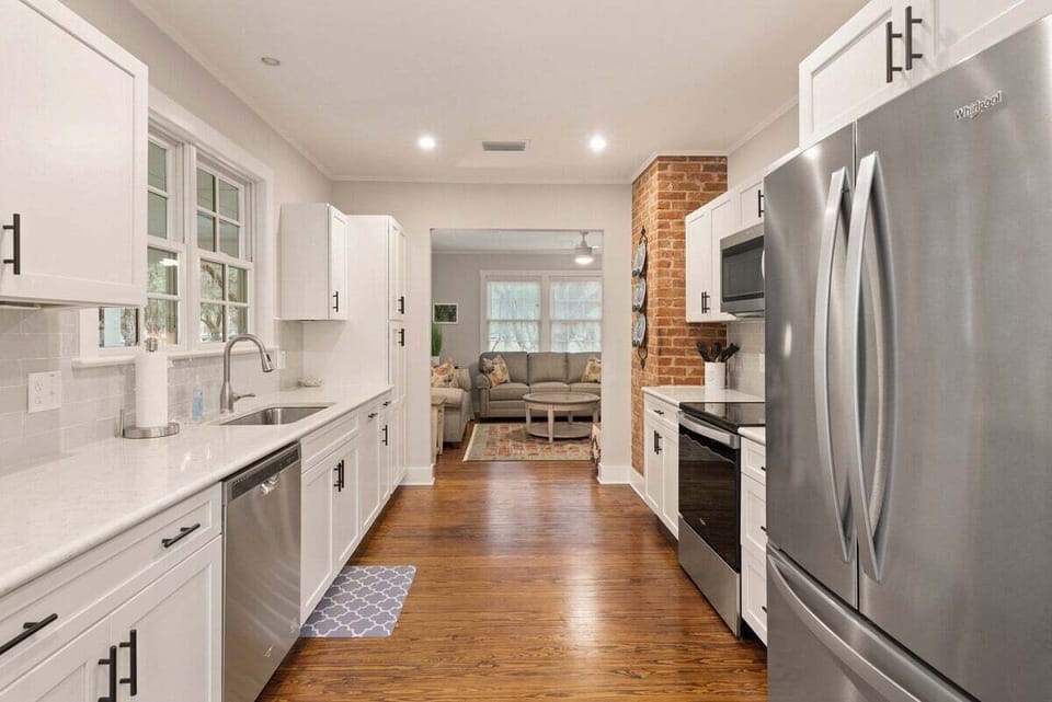 White kitchen with stainless fridge and brick fireplace wall