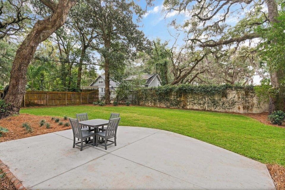Backyard patio with table and chairs under trees