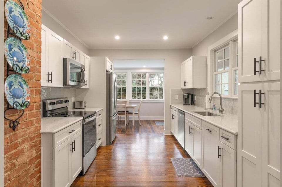 White galley kitchen with stainless appliances and brick accent wall