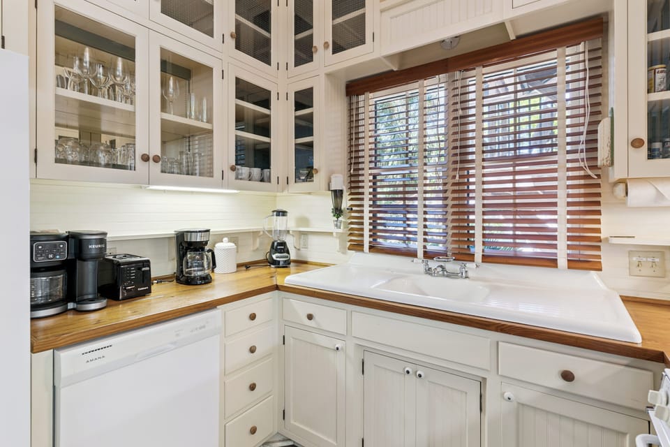 Your charming kitchen features warm wood counters, glass-front cabinets, and everything you need to brew morning coffee by the sunny window.