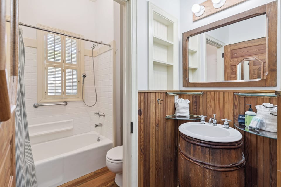 Step into your private nautical-themed bathroom featuring warm wood accents, a relaxing tub-shower combo, and thoughtful amenities for your comfort.