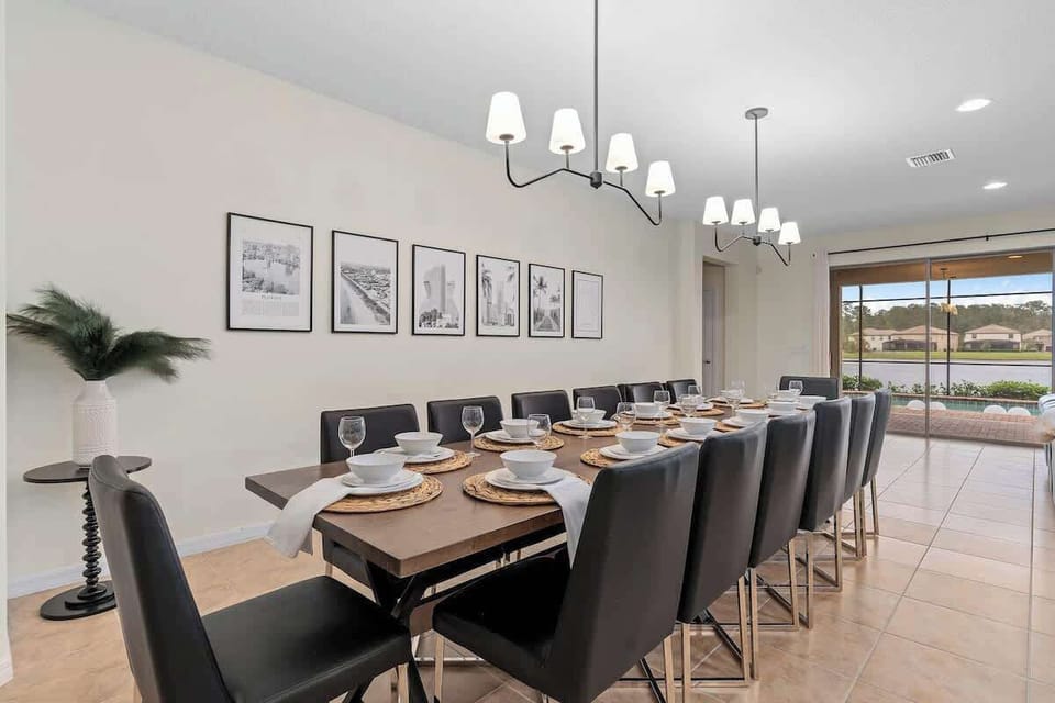 Large dining room table with seating for 14 people, plenty of lighting,  and lovely view of the pool and pond.