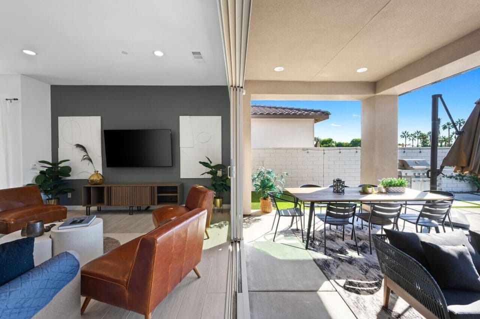 Indoor-outdoor living space w/ seating & TV, opening fully to the patio