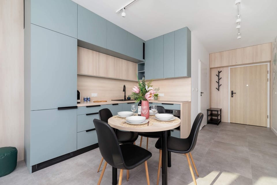A dining area with a stylish table, chairs, and modern lighting, adjacent to the kitchen.
