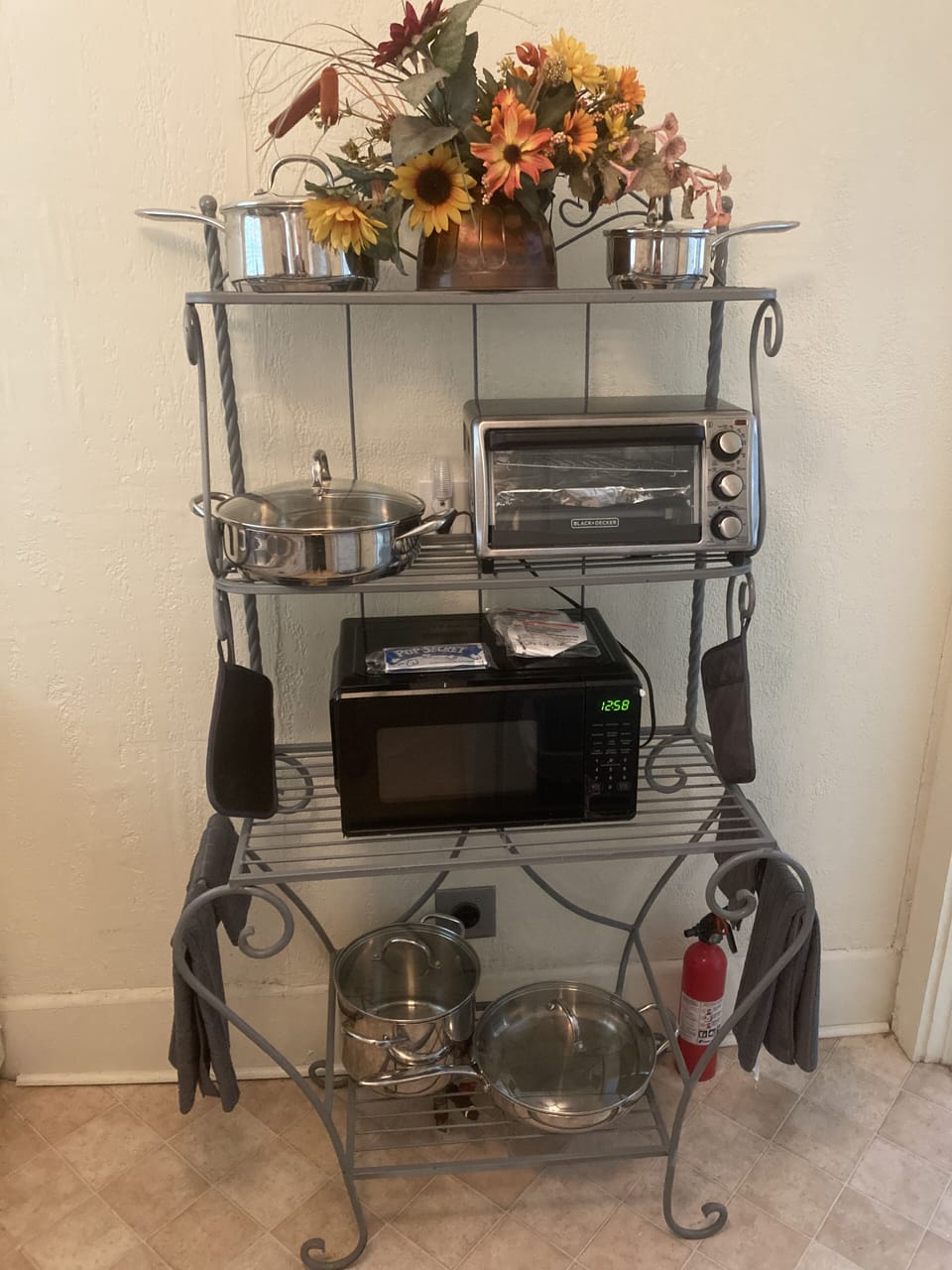 Bakers rack, microwave, toaster oven and pots and pans. 