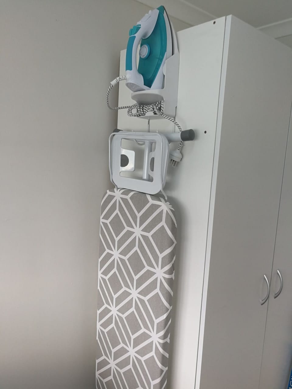 Steam iron and ironing board in laundry.