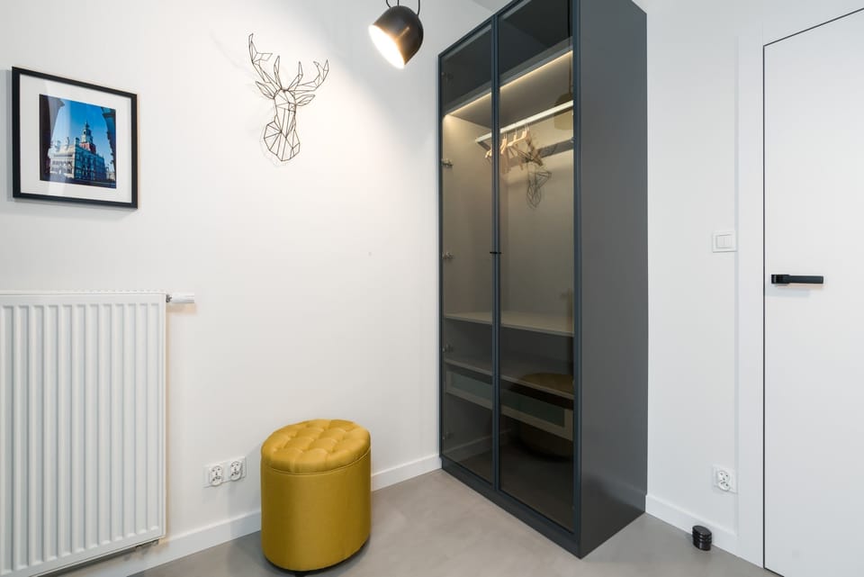 A corner with a decorative yellow stool and framed wall art.
