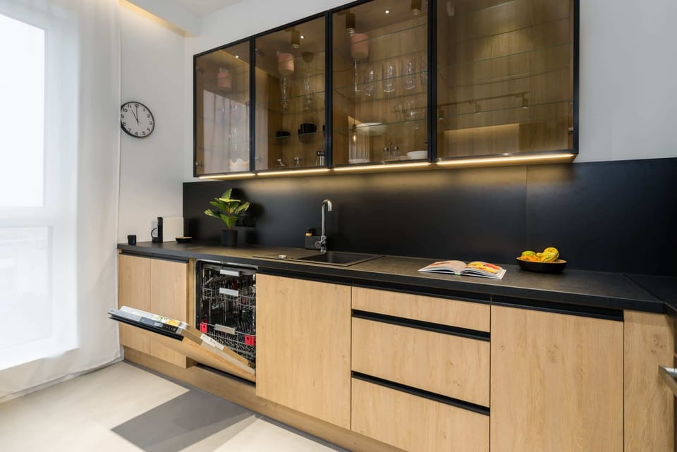 A modern kitchen with black countertops and sleek wooden cabinetry.
