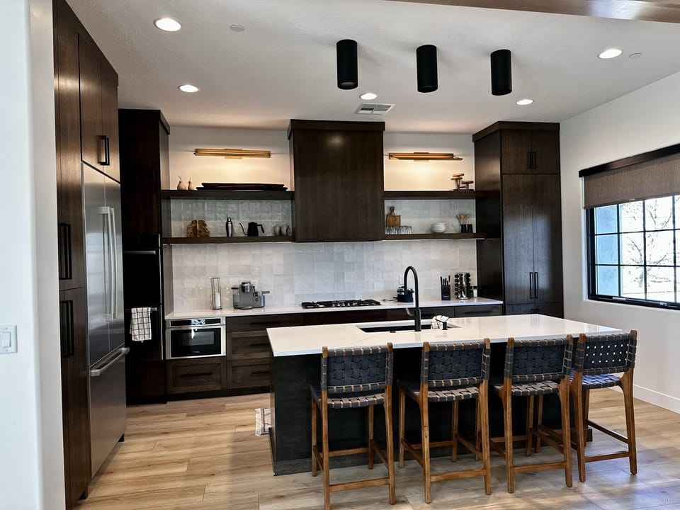 Tasteful decor, a gas range, double ovens, a large island and beautiful light