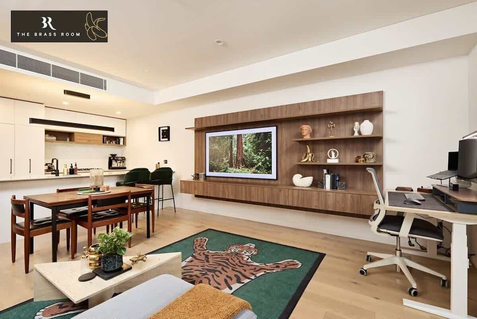 Our living room, with a brass-adorned table, boasts beautiful, relaxing chairs and a work-from-home setup. It's a comfortable and stylish space for both relaxation and productivity.