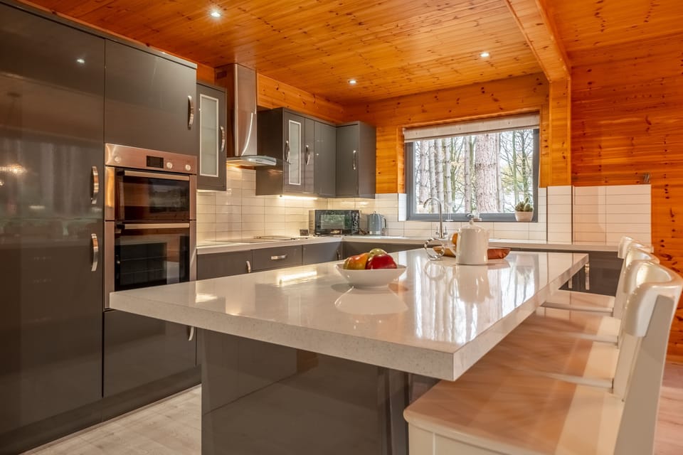 Ground floor: Kitchen with electric oven, induction hob, washing machine, dishwasher, microwave, fridge-freezer and central storage island with breakfast bar to one side with four high stools