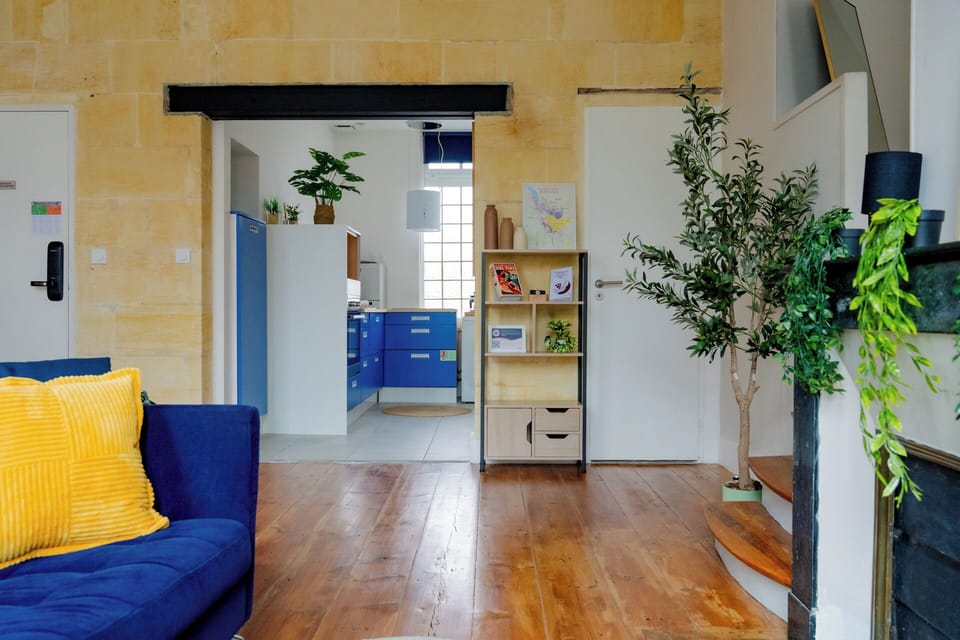 Sunny loft with bold blue kitchen, wood floors, and lush plants
