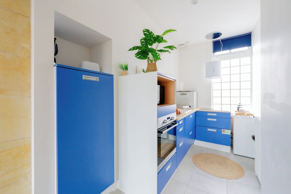 Bright, modern galley kitchen with bold blue cabinets and natural light