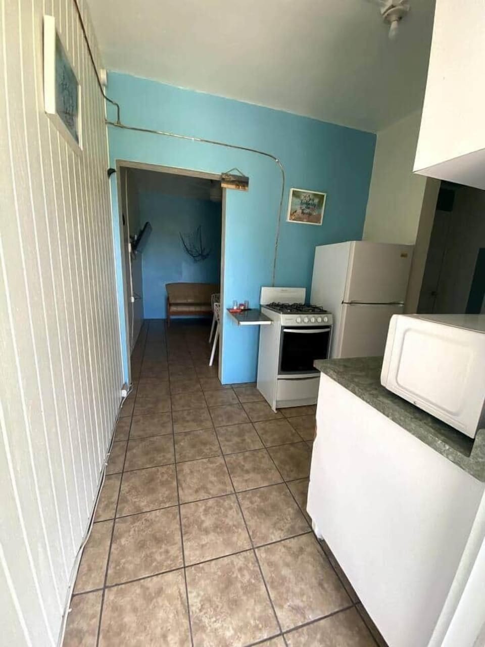Equipped kitchen with a refrigerator, gas stove, microwave, coffee pot and utensils for cooking and small breakfast area for 2.