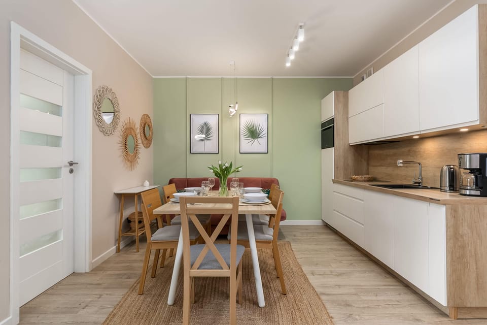 A kitchen with clean white cabinets, wooden accents, and a fully equipped dining area.
