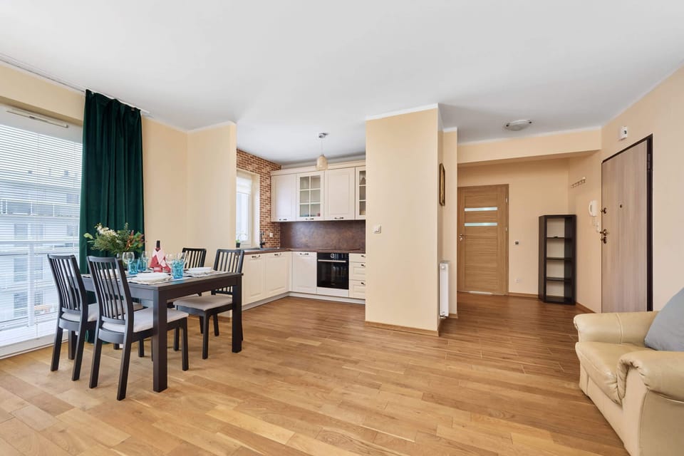 A large open-plan living and dining area, with a dining table and kitchen in the background.