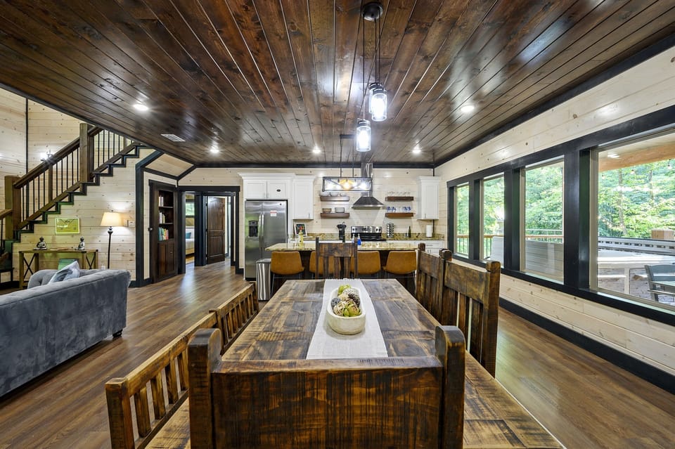 Rustic dining table with views from large windows of the surrounding trees.