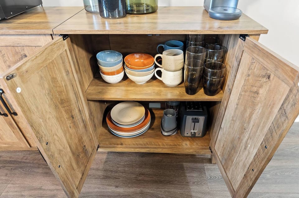 Colorful ceramic plates, cups, and bowls are located inside the drawer as well as a toaster and smoothie machine, perfect for a bright and early morning breakfast!