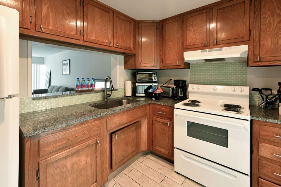 Kitchen with wood cabinets, sink, stove, and coffee maker