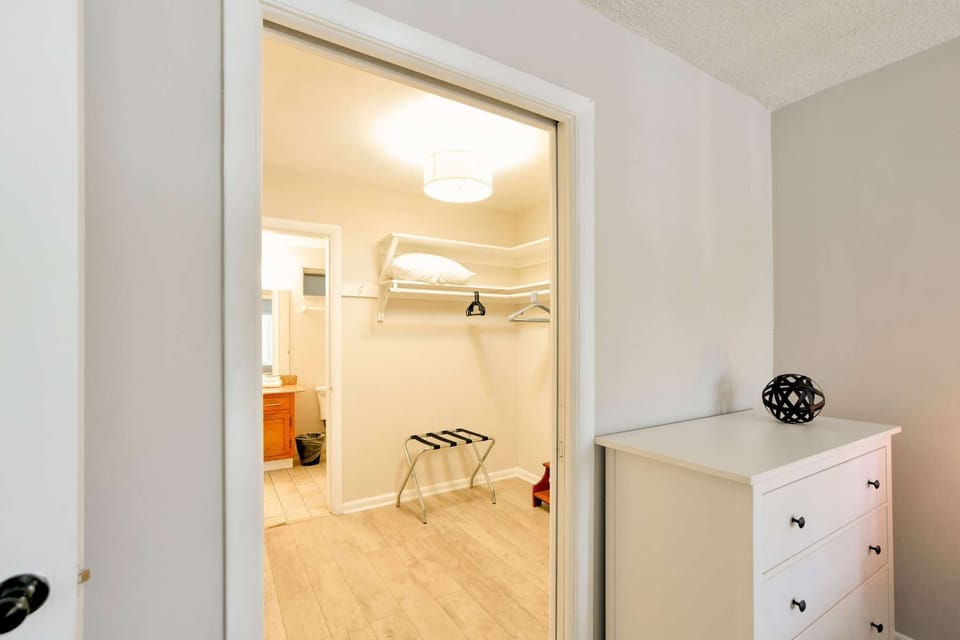 Open closet area with dresser, shelves, and bathroom entry