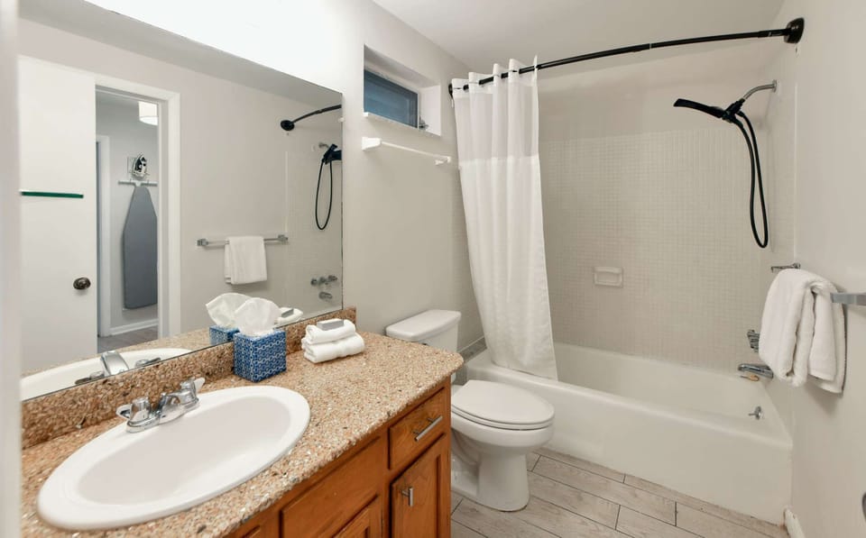 Clean bathroom with tub, sink, mirror, and fresh towels