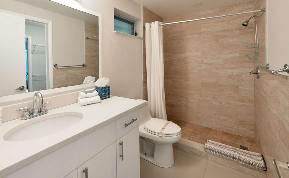 Clean bathroom with sink, toilet, shower, and large mirror